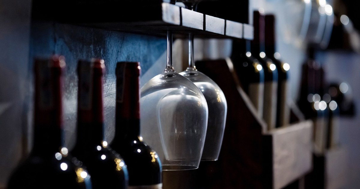 Wine glasses and bottles on the racks of a dimly lit wine cellar