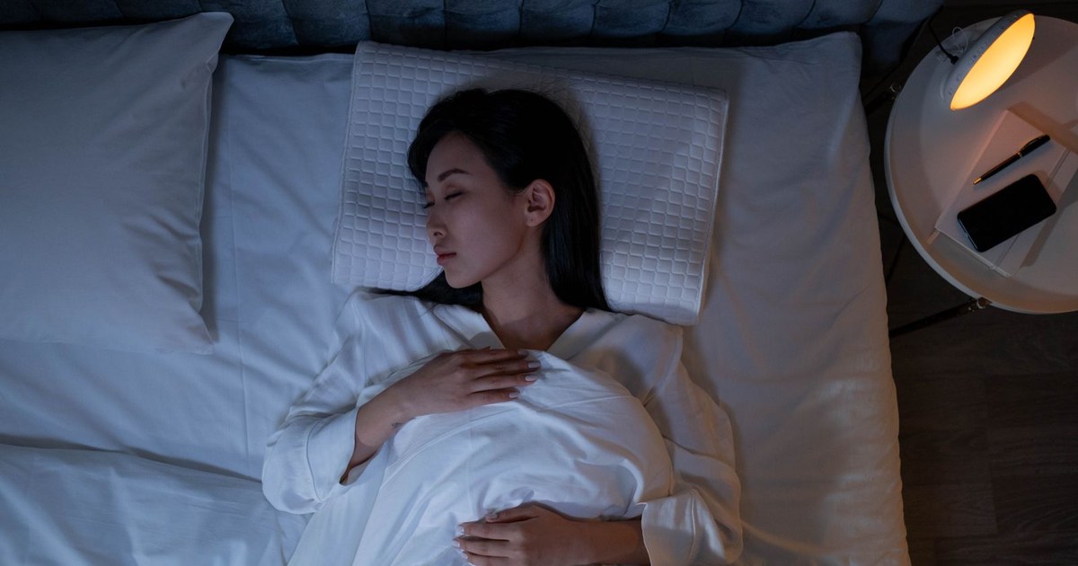 A woman sleeping peacefully in bed under soft, dim evening lighting