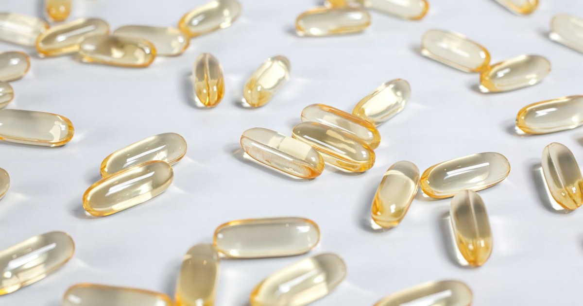 Golden yellow softgel capsules scattered across a plain white surface