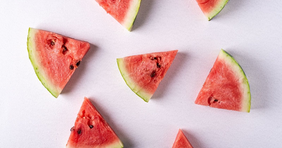 Triangular watermelon slices scattered on a pale gray surface, seen from above