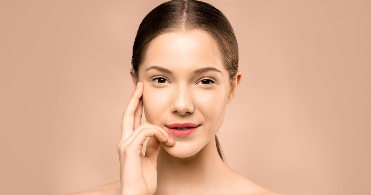 A woman with healthy, glowing skin touching her cheek