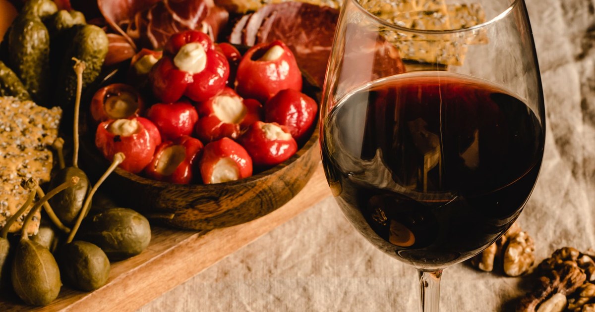 Red wine, cured meat, aged cheese, capers and olives on a wooden board, all foods high in histamine