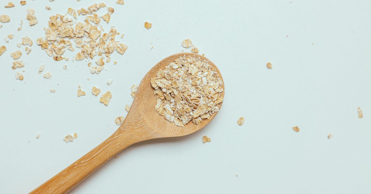 Oat flakes in a wooden spoon on a light surface