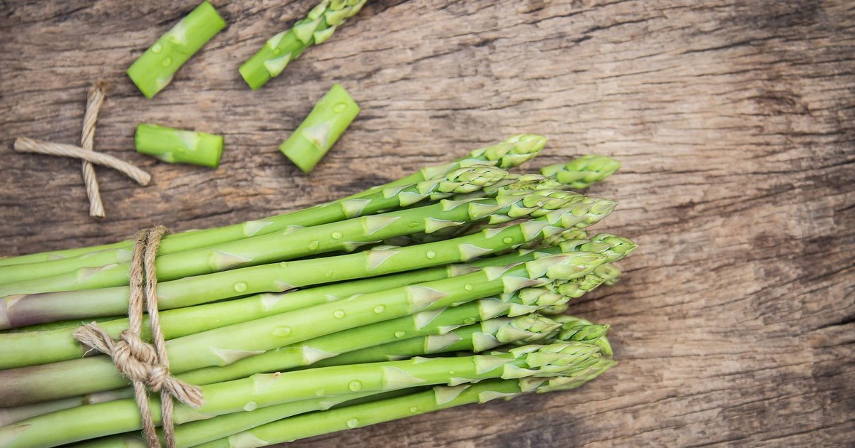 A twine-tied bundle of fresh green asparagus spears on a rustic wooden table