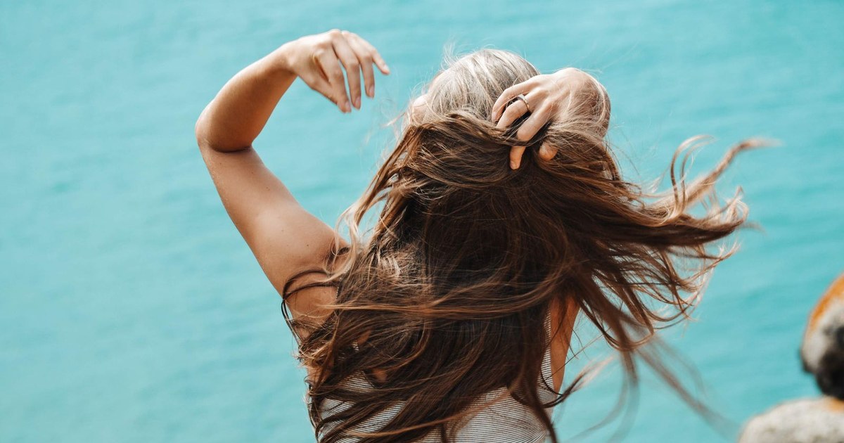 A woman running her hand through her long, glossy brown hair