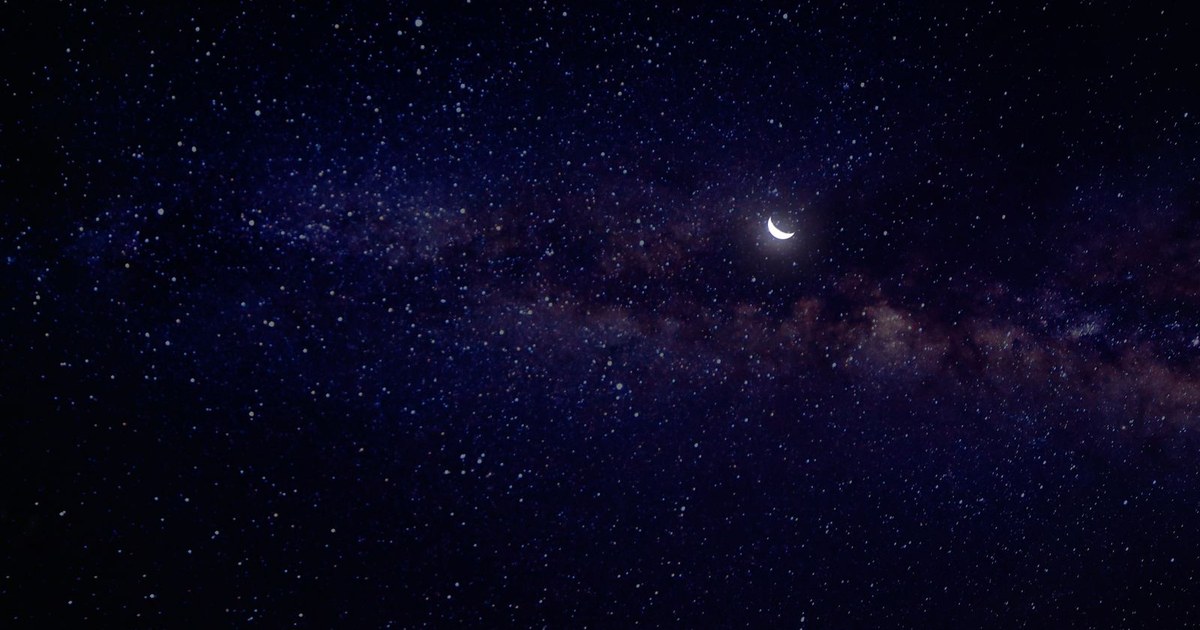 A bright crescent moon in a deep blue starry night sky