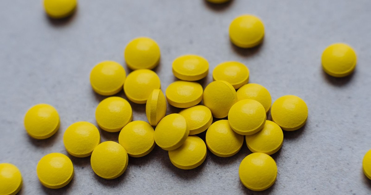 Bright yellow round tablets scattered on a gray surface
