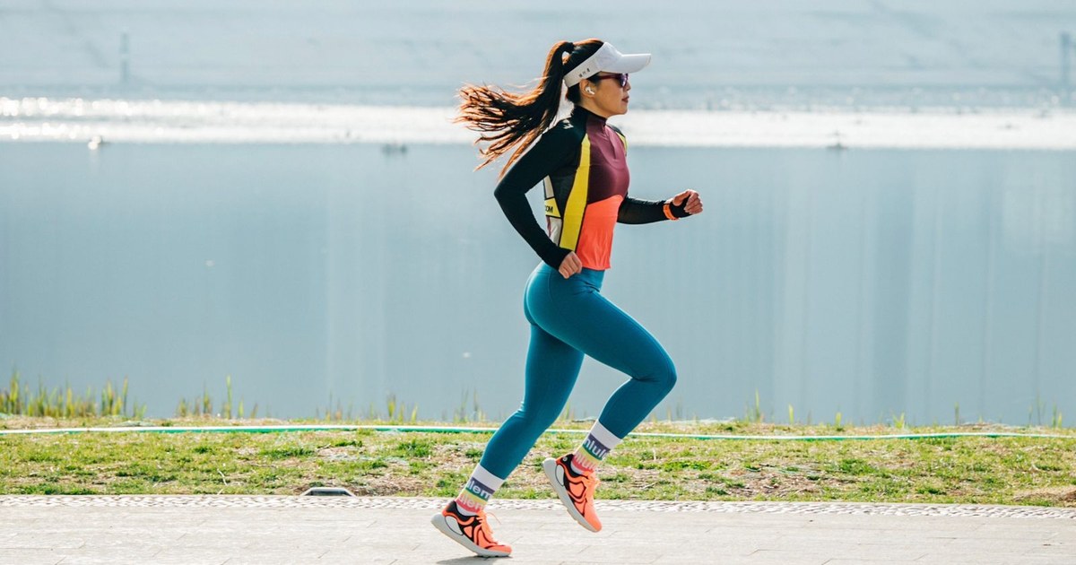 An active woman running along a sunny lakeside path, illustrating skin and joint health from an active lifestyle