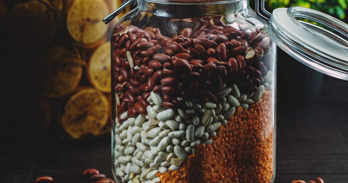 A glass jar layered with assorted dried beans, lentils, and other legumes