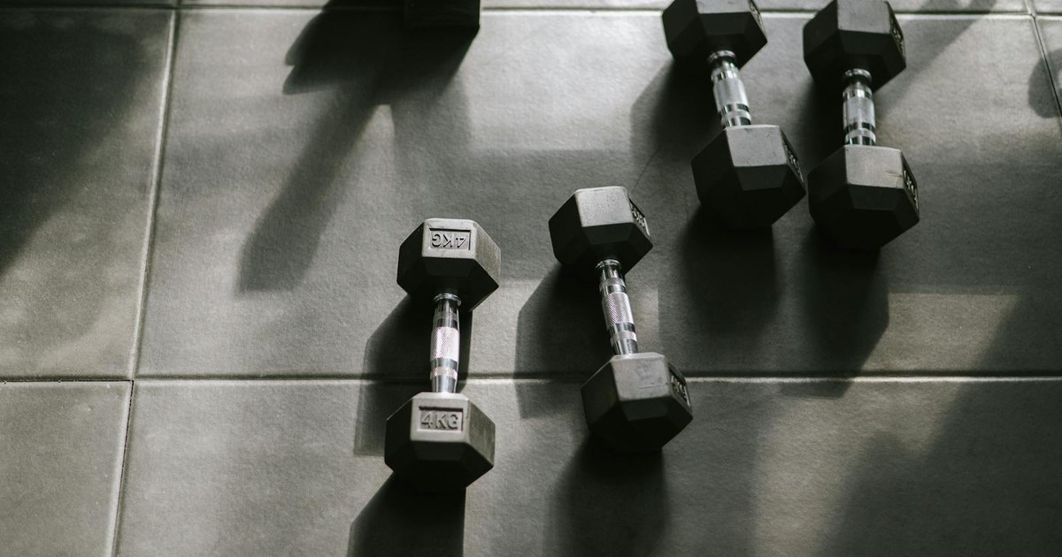 Black hex dumbbells on a gym floor in dramatic side light