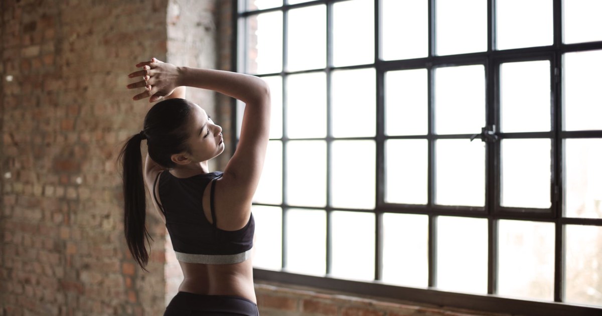 A woman stretching energetically in bright morning light
