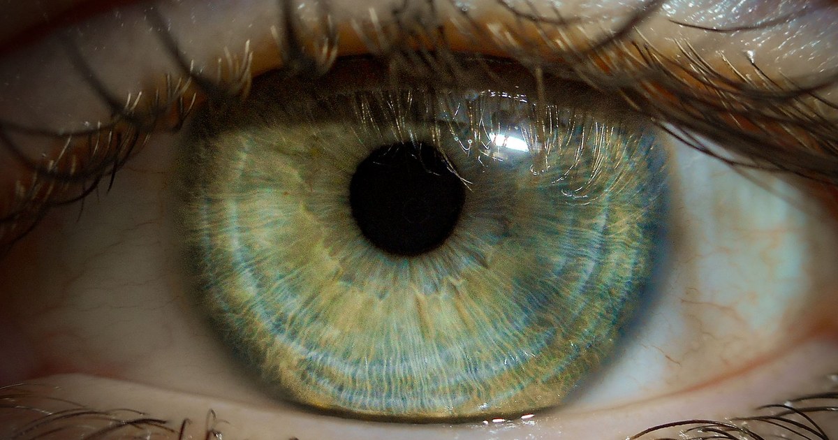 A close-up of a human eye with a green iris in soft light