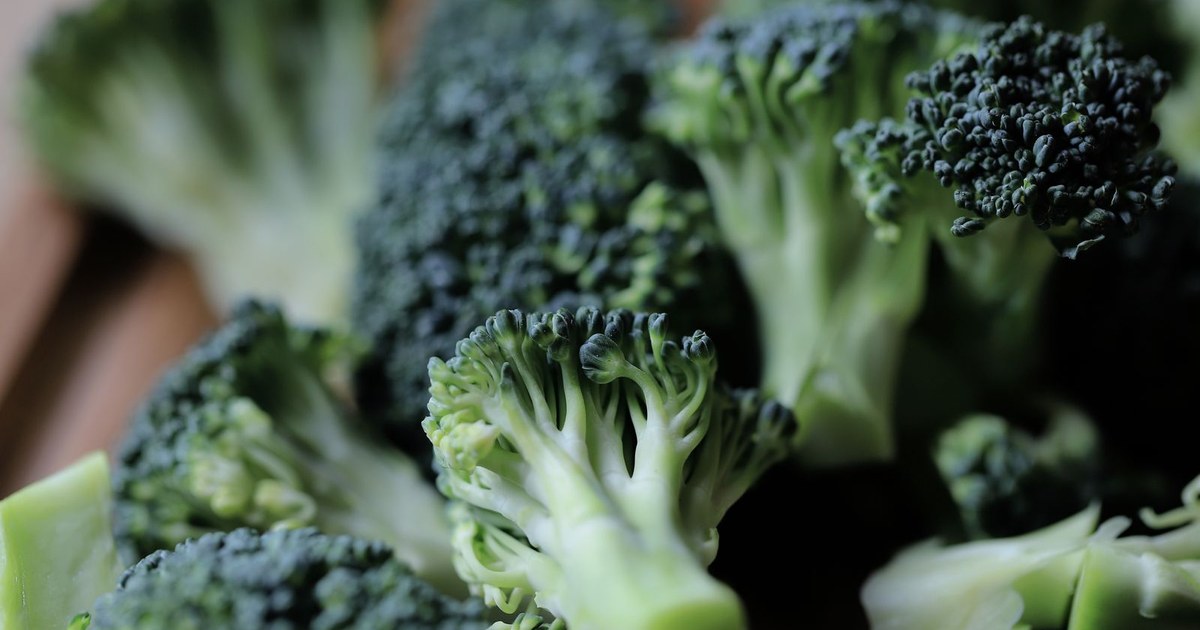 Close-up of fresh green broccoli florets on a wooden cutting board, a cruciferous vegetable rich in glucoraphanin, the precursor to sulforaphane