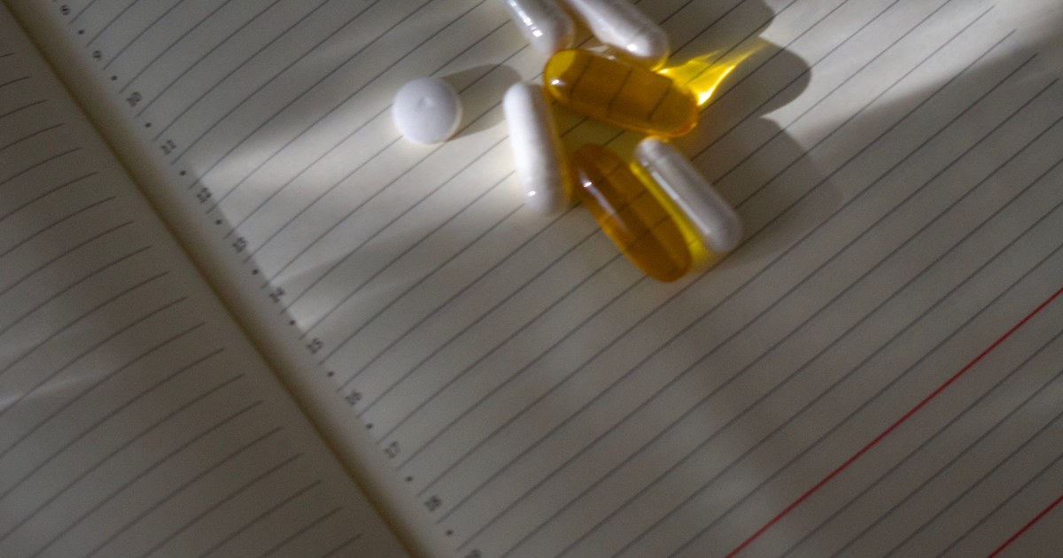 Supplement capsules and softgels scattered on an open lined planner
