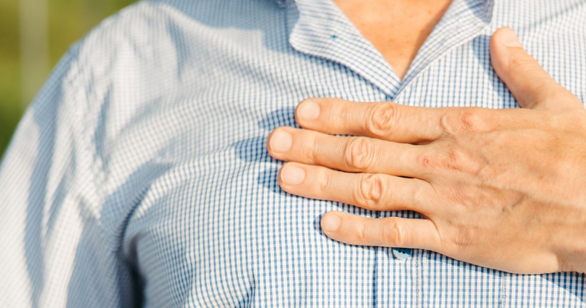 A person pressing a hand flat against the chest over the heart
