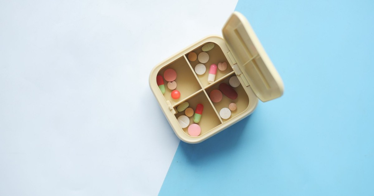 An open pill organizer filled with assorted colorful supplements