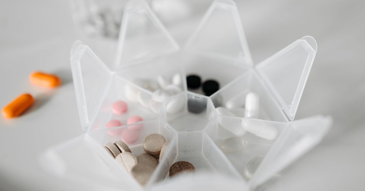 A weekly pill organizer filled with assorted supplements
