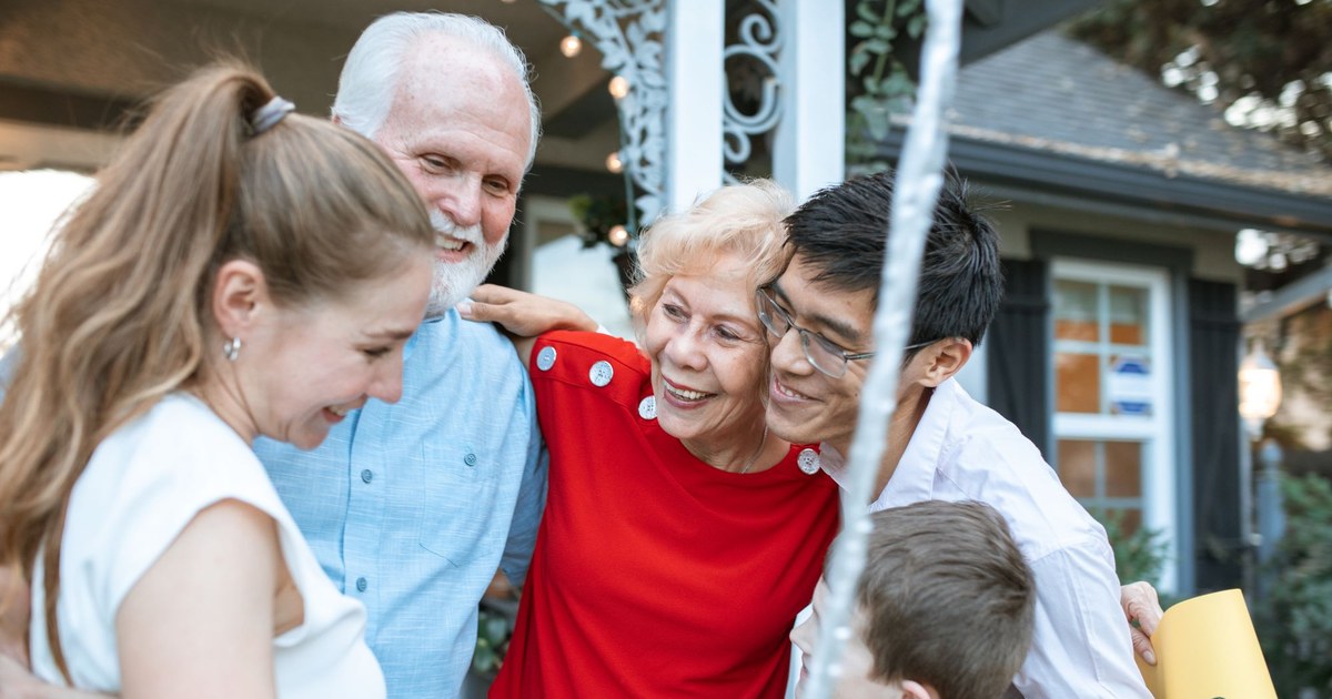 Three generations of a family smiling together outdoors