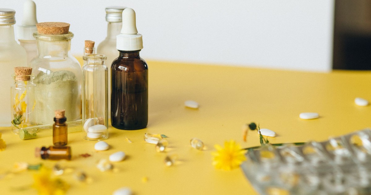 Apothecary bottles and scattered supplement pills on a yellow surface