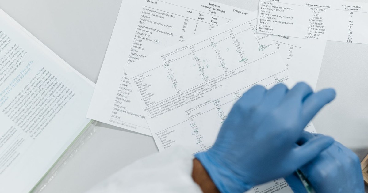 Gloved hands reviewing a cholesterol and lipid blood test report