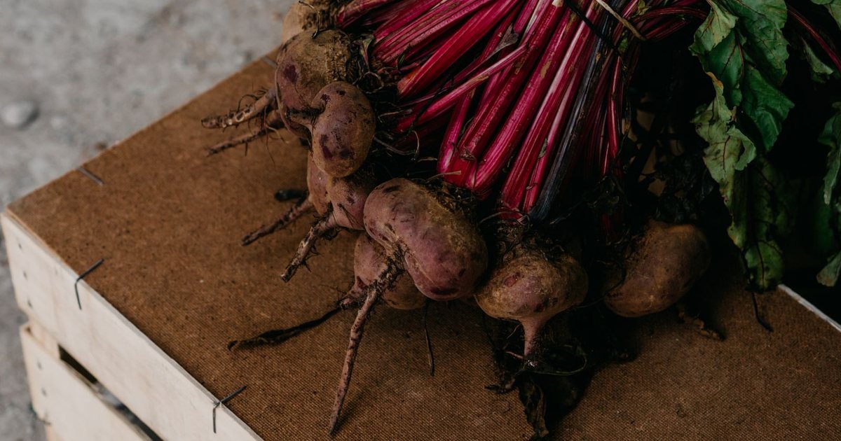 Fresh red beets with green leafy tops in a wooden crate