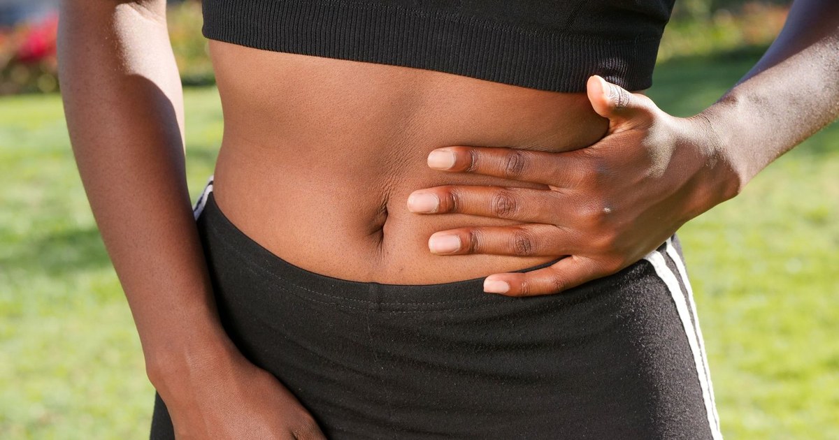 A person in activewear resting a hand on their midsection outdoors